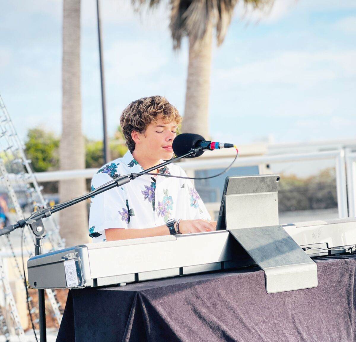 Makena Stumpo playing his electronic keyboard and singing for a public audience.