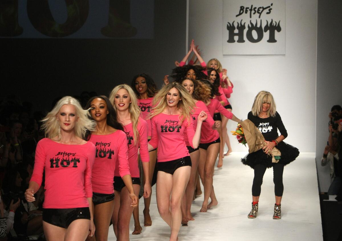 A file photo of designer Betsey Johnson, right, at the runway finale of her show on March 13, 2014, during Style Fashion Week at LA Live last season. Organizers have just announced that this season's shows will take place at the Reef LA on South Broadway.