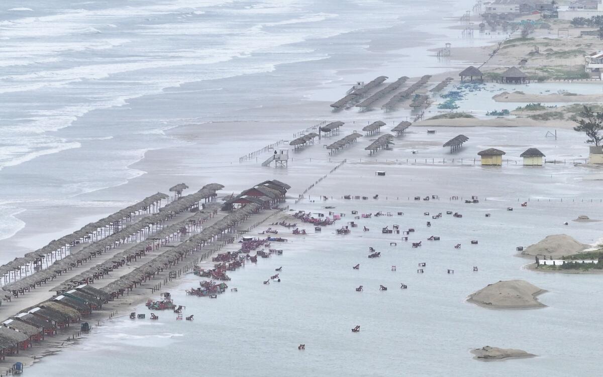 Beach furniture is strewn along a flooded beach.