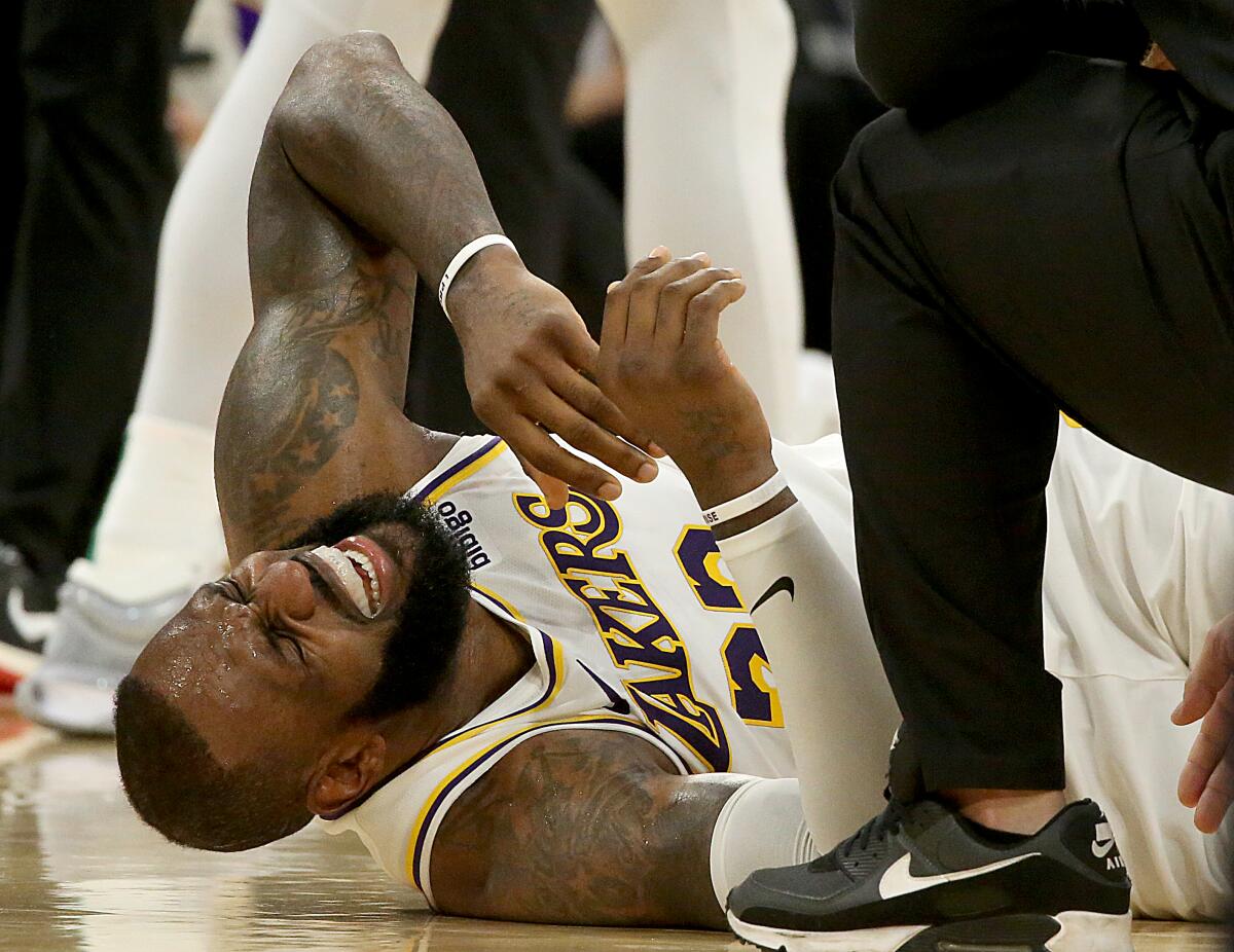 Lakers forward LeBron James grimaces in pain while lying on the court after colliding with Celtics forward Jaylen Brown.