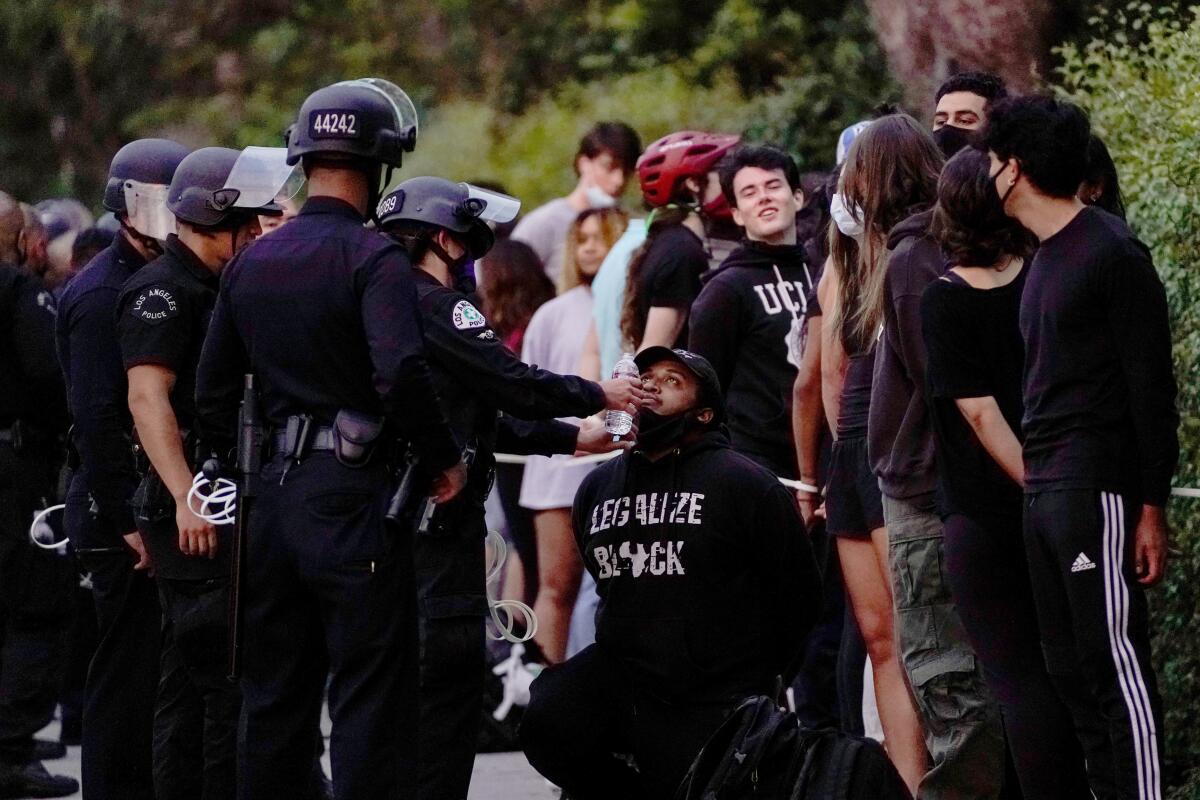 People wait to be processed by law enforcement officers on a Wilshire Boulevard sidewalk Monday in Westwood.