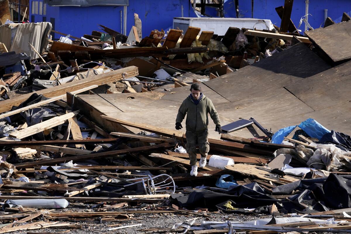 A man walks through debris and damage from a tornado