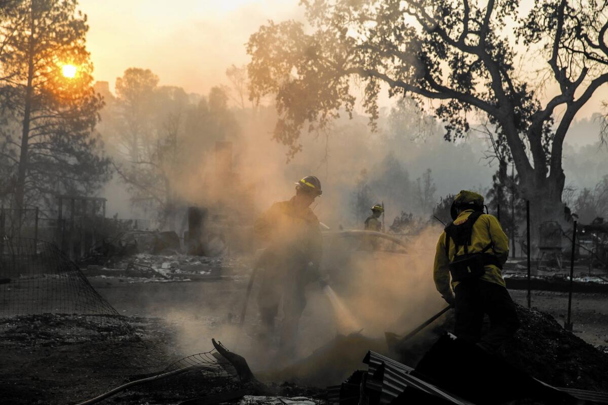 Firefighters soak potential hotspots underneath the rubble of a home in Middletown, Calif.