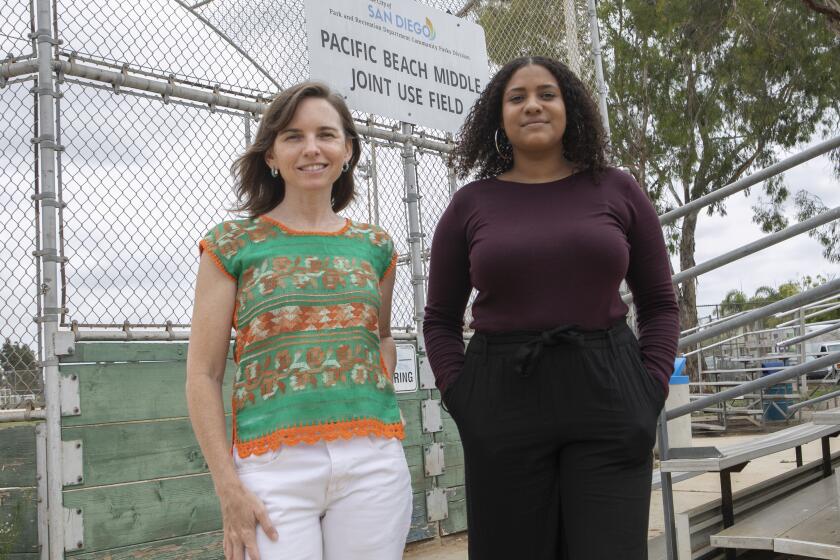 Regina Sinsky-Crosby (L) and Paige Hernandez (R) stand in front of the sign that they have petitioned to change the name to Fannie and William Payne Community Park, in Pacific Beach.