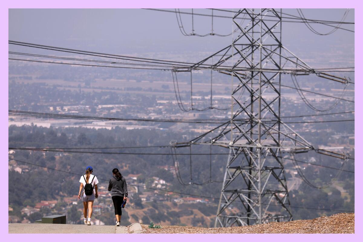 A pair of hikers walk down a road near some power lines. 