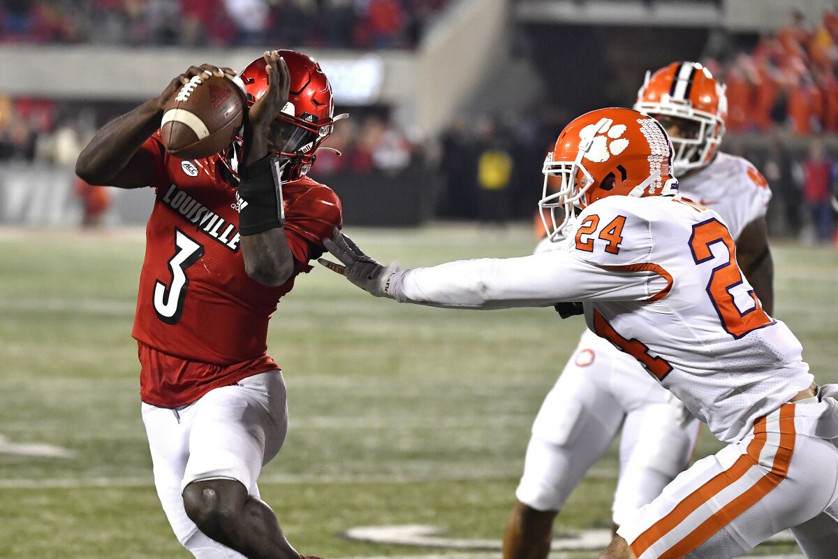 Louisville quarterback Malik Cunningham (3) avoids the grasp of Clemson safety Nolan Turner (24) during the second half of an NCAA college football game in Louisville, Ky., Saturday, Nov. 6, 2021. (AP Photo/Timothy D. Easley)