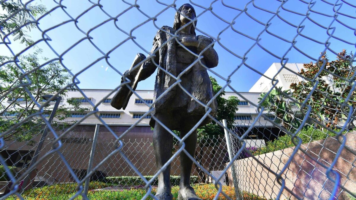 A statue of Christopher Columbus in downtown Los Angeles is surrounded by chain-link fence on Oct. 9, 2017.