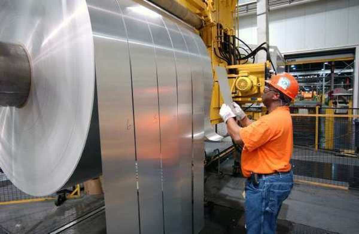 An Alcoa employee inspects finished rolls of aluminum as they come off the production line. Alcoa reported a first-quarter profit Tuesday.