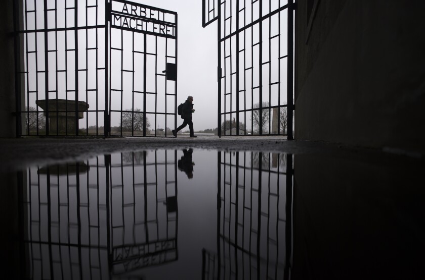A person walks behind the gate of the Sachsenhausen Nazi death camp with the phrase 'Arbeit macht frei' (work sets you free) in Oranienburg, about 30 kilometers (18 miles) north of Berlin, Germany, Tuesday, Jan. 25, 2022. On Thursday Jan. 27, 2022 the International Holocaust Remembrance Day marks the liberation of the Auschwitz Nazi death camp on Jan. 27, 1945. (AP Photo/Markus Schreiber)