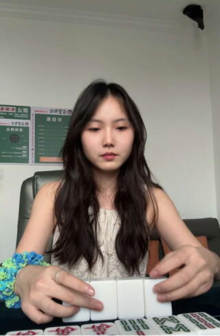 Amora Liu sits at a table playing mah-jongg