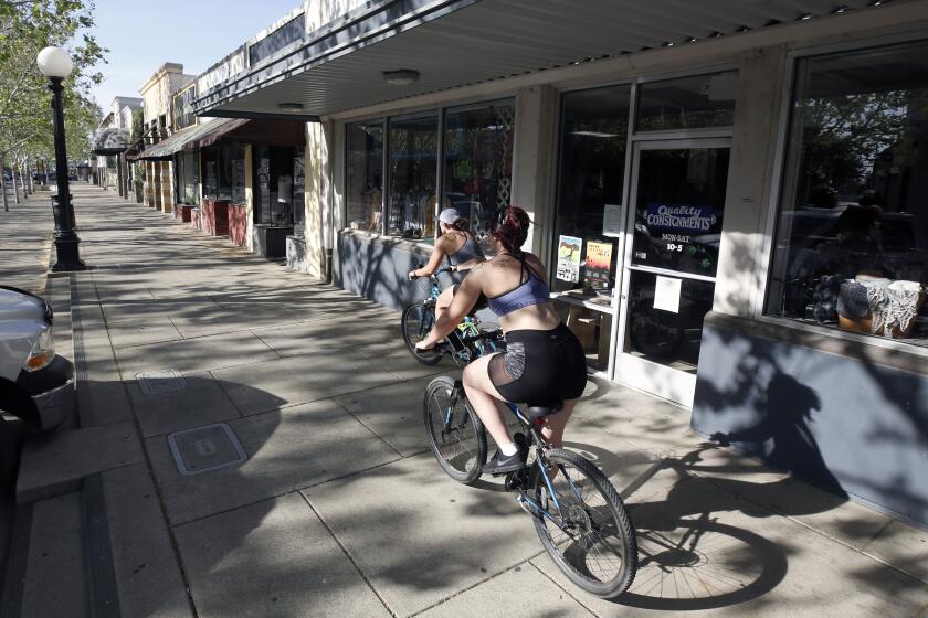 A pair of bicyclists ride past closed businesses on Plumas Street in Yuba City, Calif., Monday, April 27, 2020, during the coronavirus outbreak. Representatives of Sutter County, where Yuba City is located, joined five other counties calling on Gov. Gavin Newsom to allow them to exercise local authority to implement a careful and phased reopening of the local economies. (AP Photo/Rich Pedroncelli)