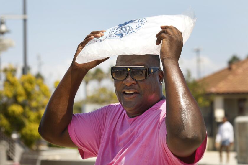 Los Angeles, California-Sept 5, 2022-Craig Sylve, of Long Beach, carries a bag of ice on his head at Cabrillo Way Marina in San Pedro, CA, on Sept. 5, 2022. As temperature remains high on Labor Day 2022, people had to the waterfront for relief, Sept. 5, 2022. (Carolyn Cole / Los Angeles Times)