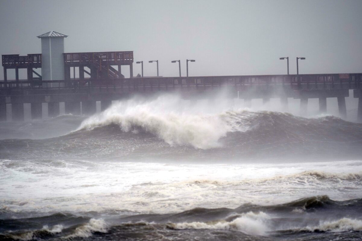 Waves crash near a pier, at Gulf State Park, Tuesday, Sept. 15, 2020, in Gulf Shores, Ala. Hurricane Sally is crawling toward the northern Gulf Coast at just 2 mph, a pace that's enabling the storm to gather huge amounts of water to eventually dump on land. (AP Photo/Gerald Herbrt)