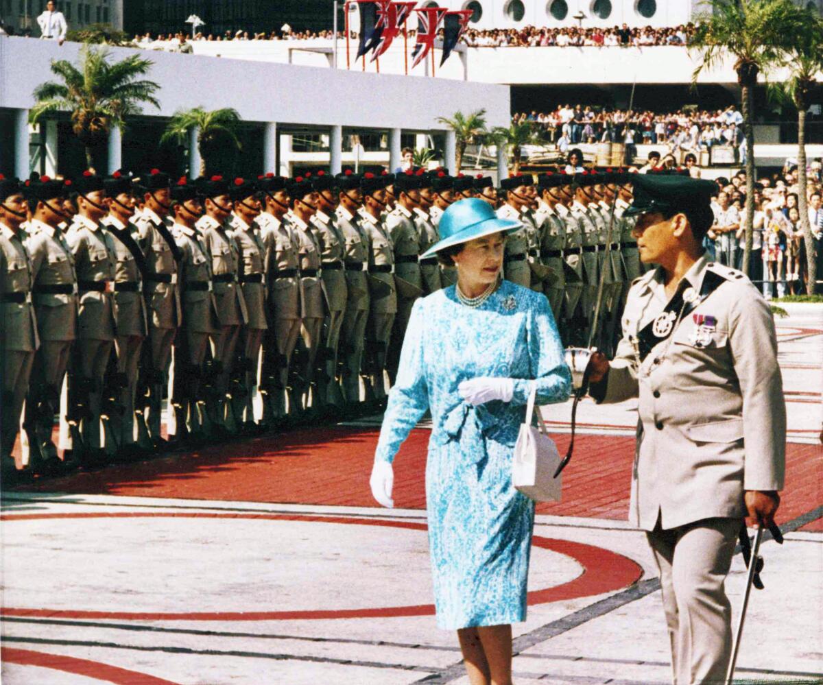 The queen talks to an officer while walking past a line of soldiers.