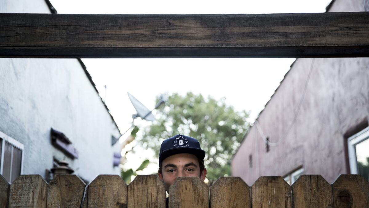 Milo Schwartz behind his family's redwood gate, which is considered a blight on the neighborhood according to a notice left by code enforcement officials.