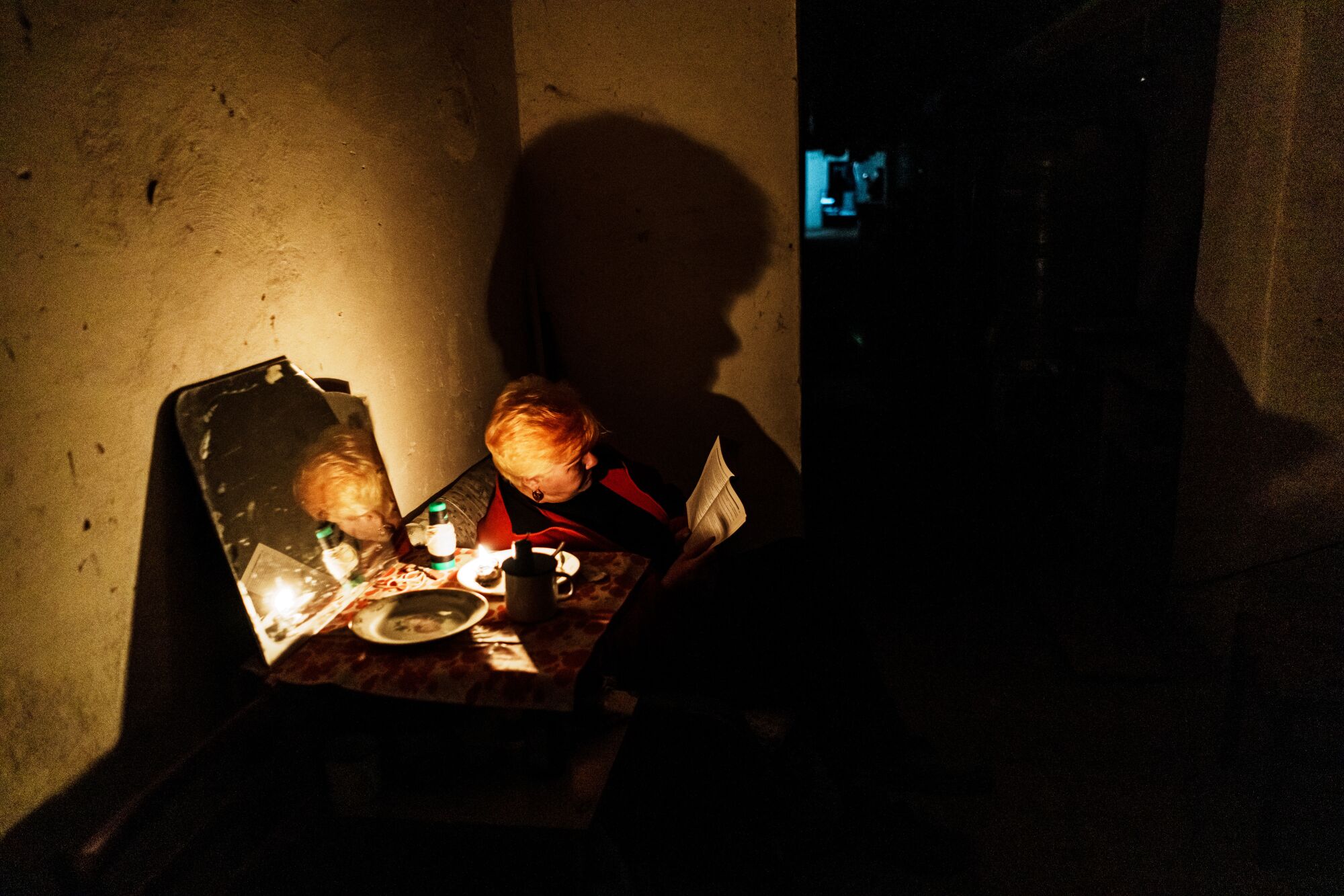 A woman reads a book underground in a mostly dark room