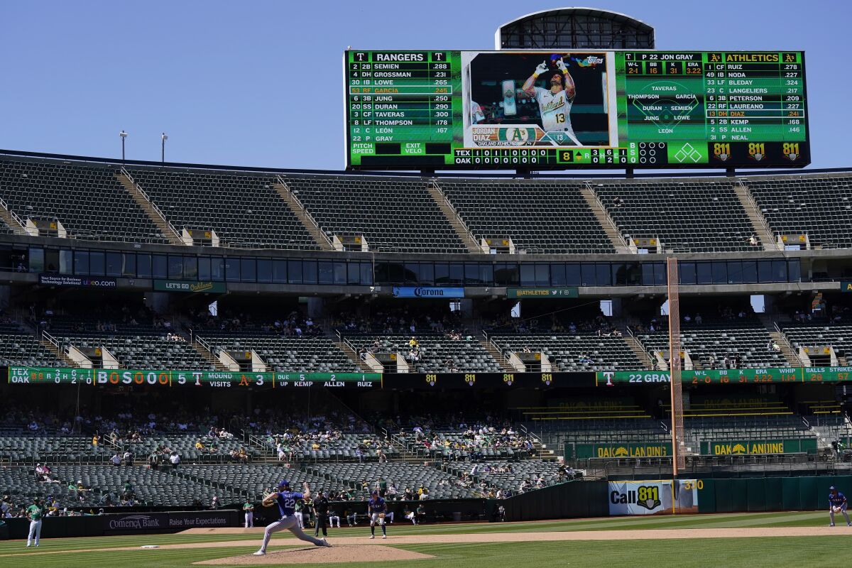 Texas Rangers pitcher Jon Gray throws to an Oakland Athletics batter in a game that is not well attended in Oakland
