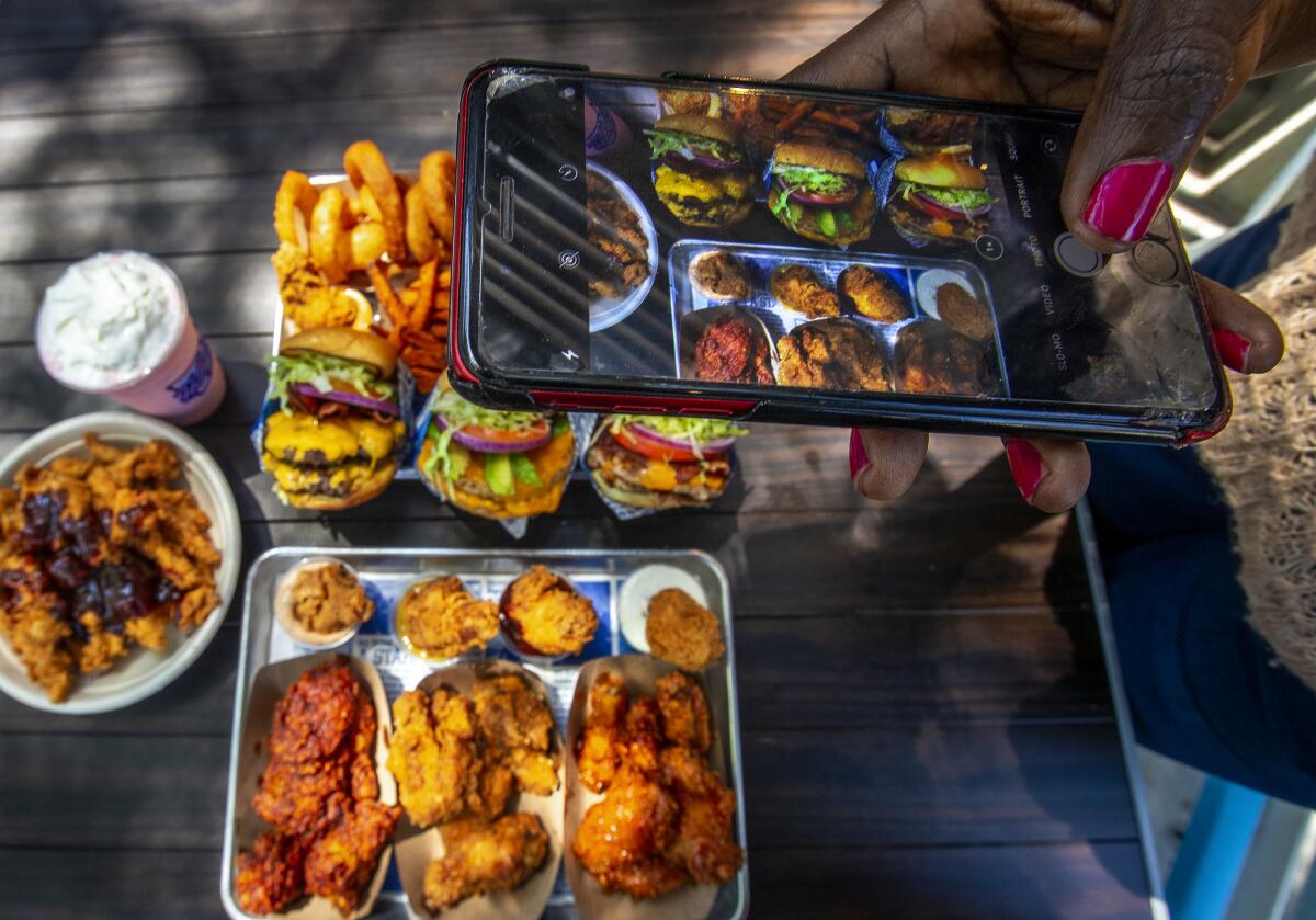 A food influencer takes photos of chicken and burgers