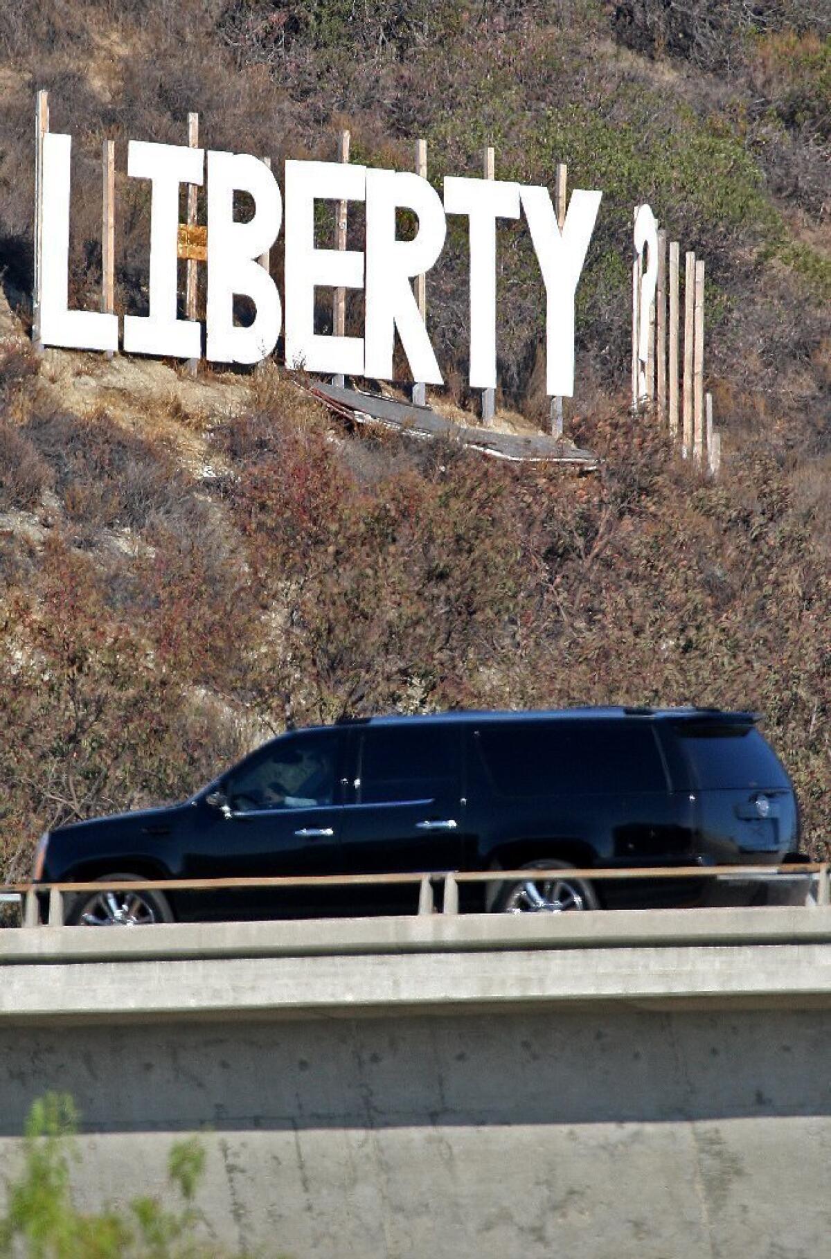 Traffic passes by a sign that reads "LIberty?" on a hillside at the intersection of the 134 and 2 freeways on Wednesday August 21, 2013.
