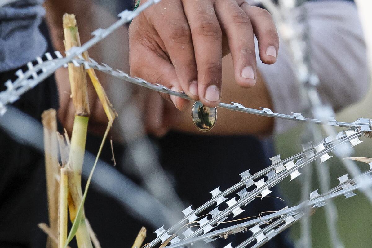 A hand gingerly touches razor wire.