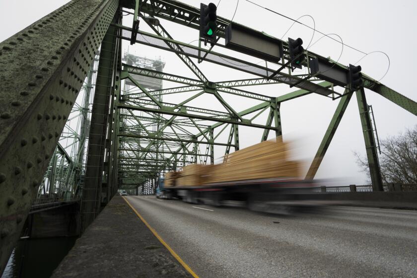 ARCHIVO - Un camión maderero pasa por un puente de la Interestatal 5 sobre el río Columbia, que conecta Portland, Oregon, con el suroeste del estado de Washington, el 13 de febrero de 2024. Docenas de puentes envejecidos en 16 estados, incluido este en la Interestatal 5, serán reparados o sustituidos con ayuda de los 5.000 millones de dólares en subvenciones federales anunciadas el miércoles 17 de julio de 2024 por el gobierno del presidente Joe Biden dentro de un gran plan de actualización de infraestructura. (AP Foto/Jenny Kane, Archivo)