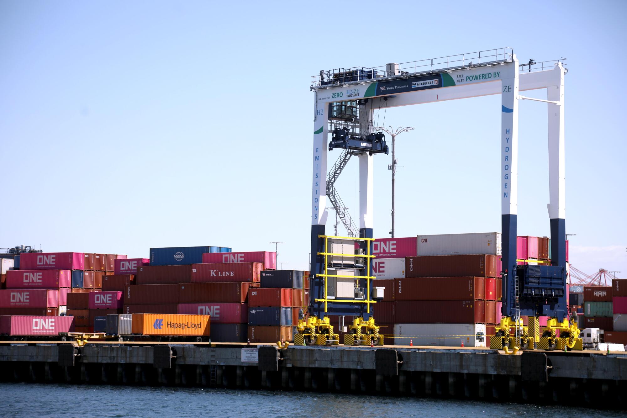 A hydrogen-powered crane moves red, orange and white shipping containers at the Port of Los Angeles. 