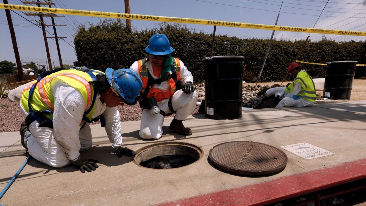Hazmat workers try to clean a storm drain that received thousands of gallons of mineral oil, a coolant for transformers, after an explosion at a DWP station in Northridge.