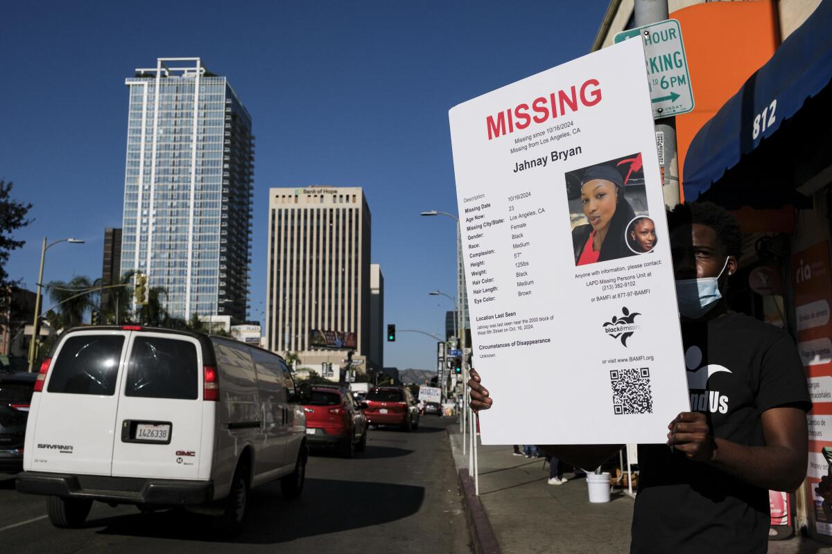 A person holds up a "Missing" sign for passing cars to see.
