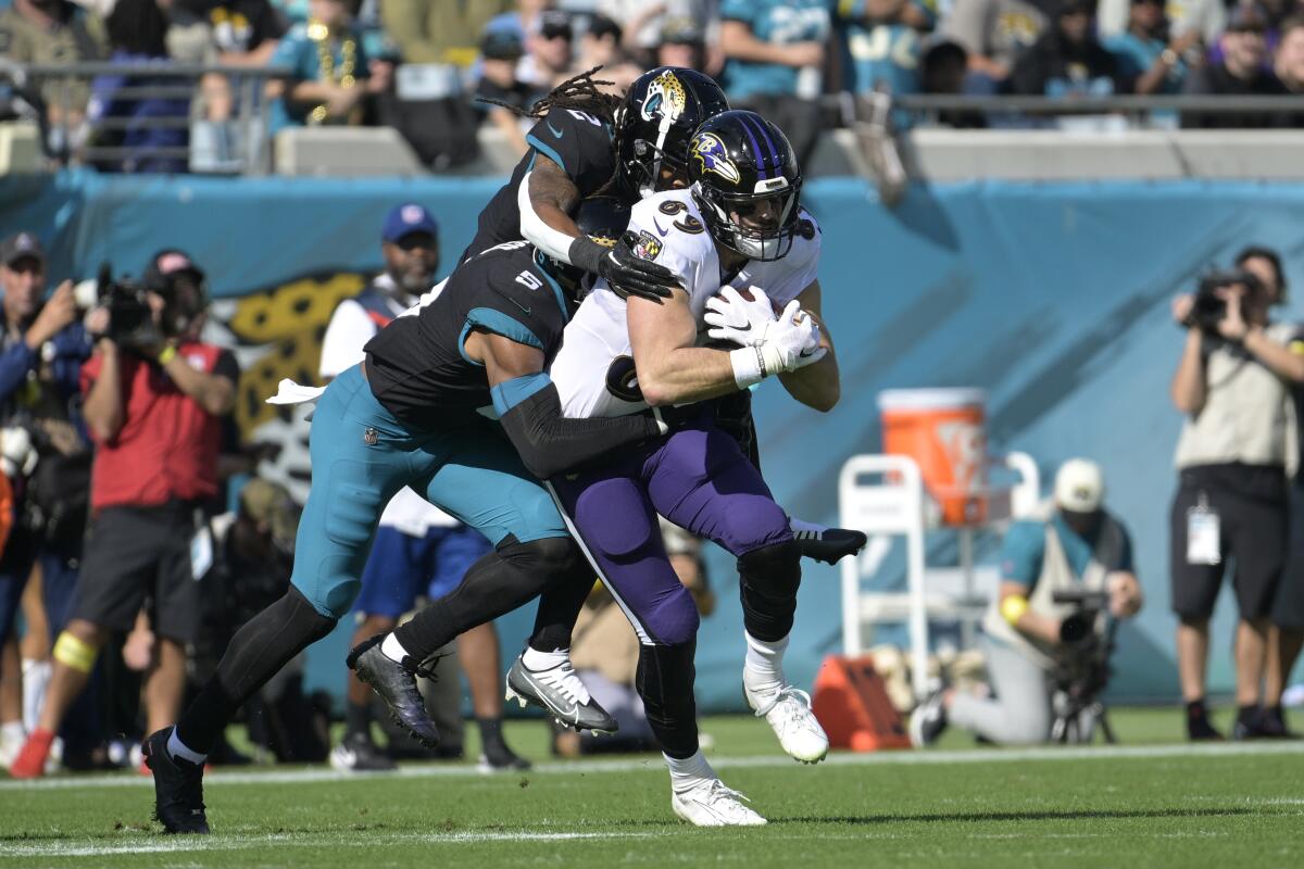 Baltimore Ravens tight end Mark Andrews is tackled by Jacksonville Jaguars safety Andre Cisco and safety Rayshawn Jenkins.