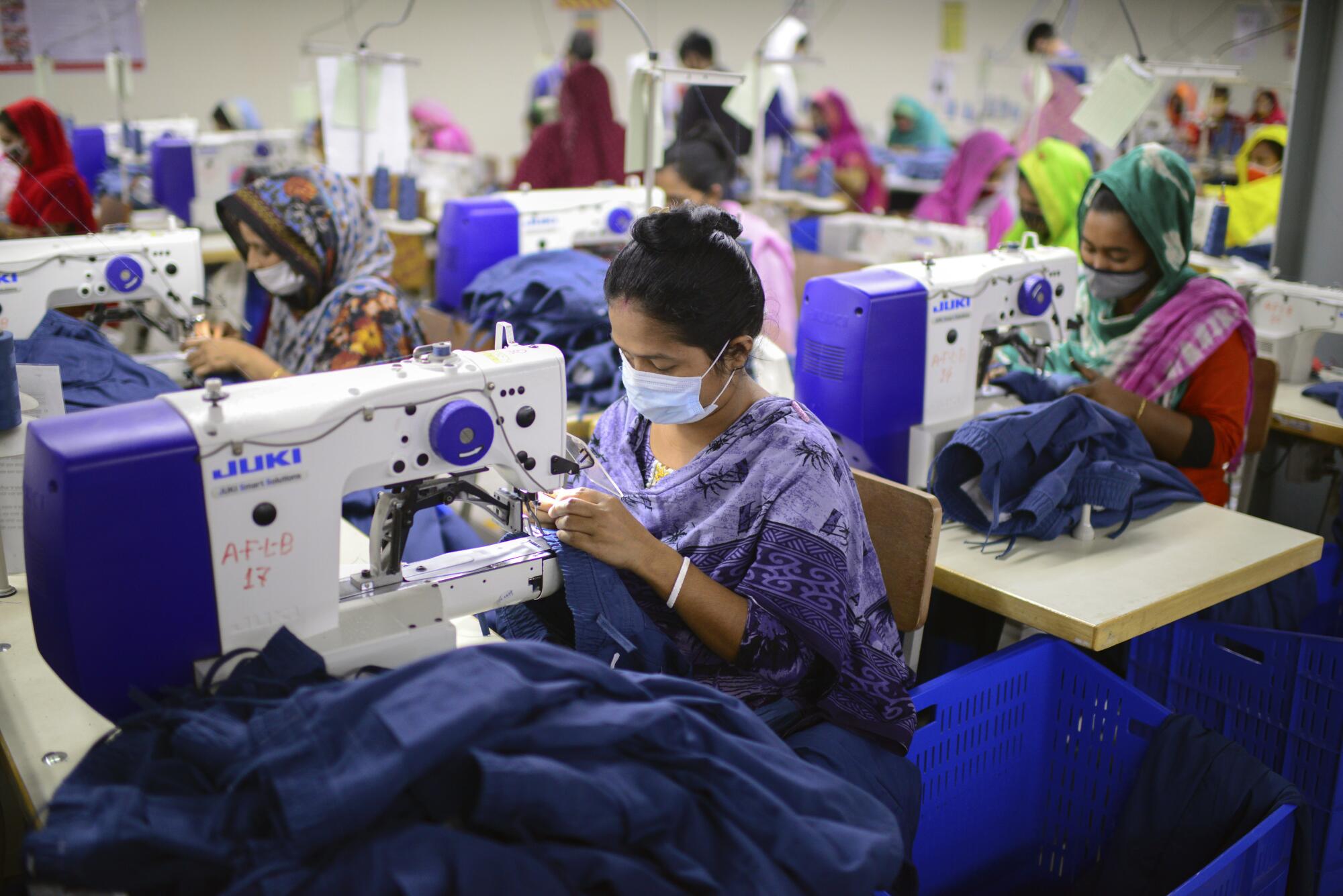 Garment employees work at sewing machines.