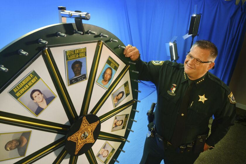 FILE - Brevard County Sheriff Wayne Ivey gets ready to spin his popular "Wheel of Fugitive" in July 2017, in Titusville, Fla. A man has filed a defamation lawsuit last week against Ivey who posts weekly “Wheel of Fugitive” videos on social media. David Gays says that he wasn’t a fugitive when his name and image appeared several times in 2021 on the sheriff’s posts inspired by the long-running TV game show “Wheel of Fortune.” (Malcolm Denemark/Florida Today via AP, File)