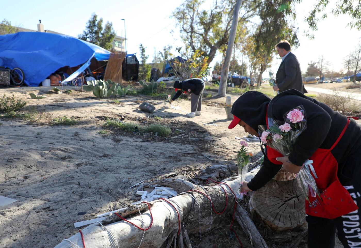 Una mujer deja flores en un campamento junto al lecho del río Santa Ana durante el 'Día de conmemoración a personas sin hogar', en Anaheim, California.