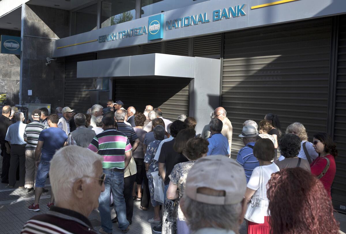 Un grupo de ancianos, que suele cobrar sus pensiones a final de mes, hacen cola ante una sucursal bancaria cerrada en Atenas, el 29 de junio de 2015. (Foto AP/Petros Giannakouris)