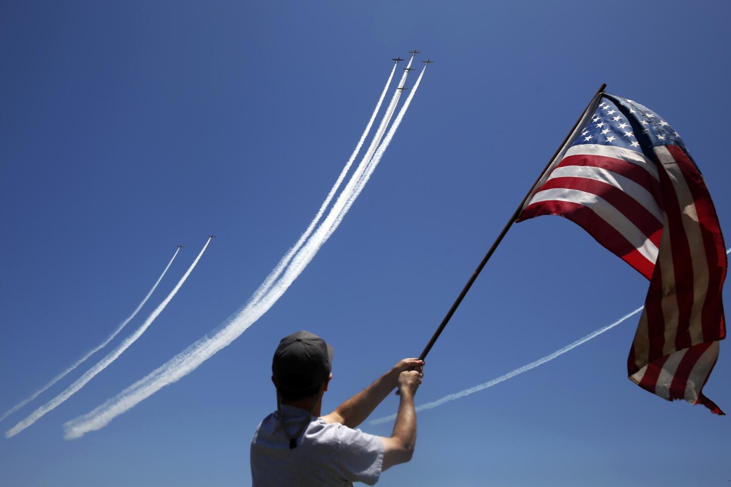 Michael Gentile waves a flag as warbirds fly over the Queen Mary on Monday in Long Beach.