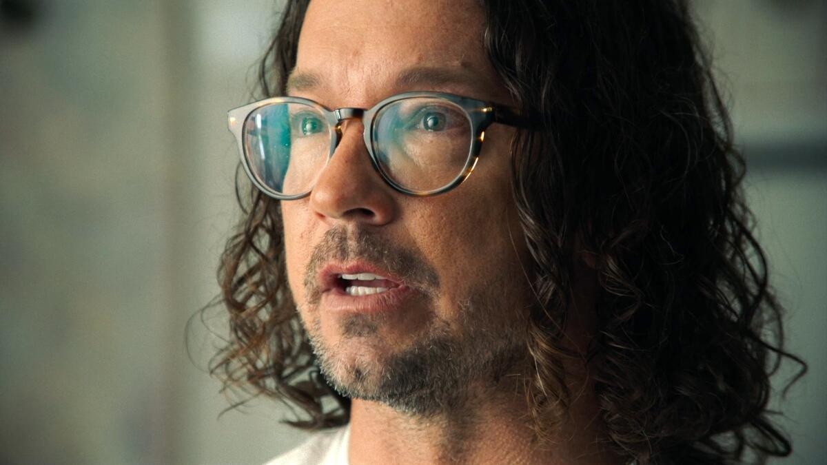 A man in glasses and shoulder length curly hair.