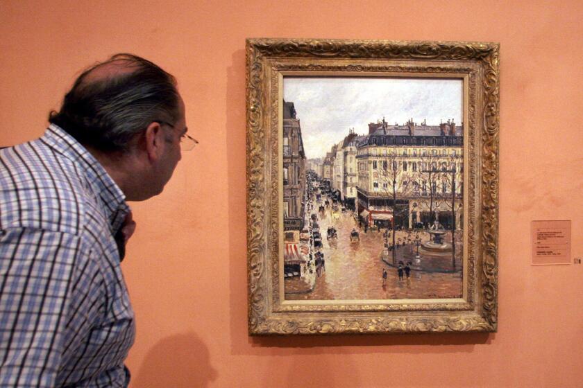FILE - This May 12, 2005 file photo shows a visitor viewing the Impressionist painting called "Rue St.-Honore, Apres-Midi, Effet de Pluie" painted in 1897 by Camille Pissarro, on display in the Thyssen-Bornemisza Museum in Madrid. A U.S. federal appeals court on Monday, Aug. 17, 2020 ruled that a priceless Camille Pissarro painting a Jewish woman traded to the Nazis to escape the Holocaust in 1939 may remain the property of the Spanish museum that acquired it in 1992. (AP Photo/Mariana Eliano, File)