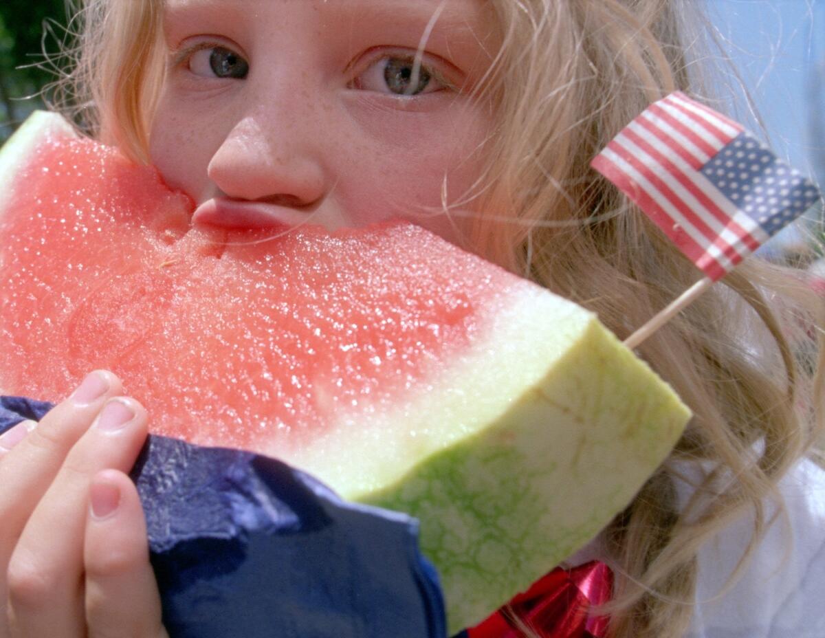 Martine Rickey, 6, of Ojai, eats a piece of watermelon at a party in Sarzotti Park.