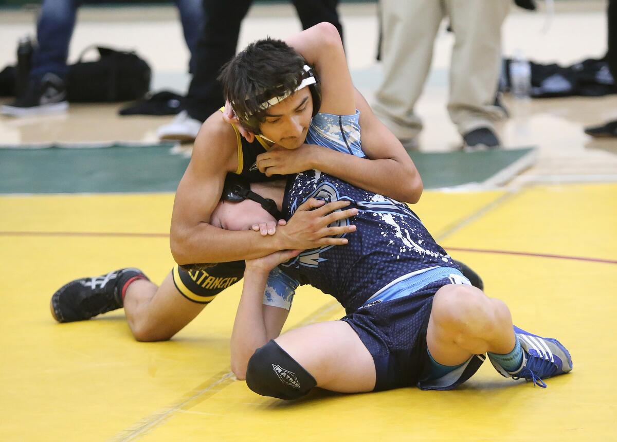 Corona del Mar's Chase Bergstrom, on bottom, wrestles Estancia's Gio Ocampo in a 120-pound match of the Newport-Mesa District championships on Wednesday at Costa Mesa High.