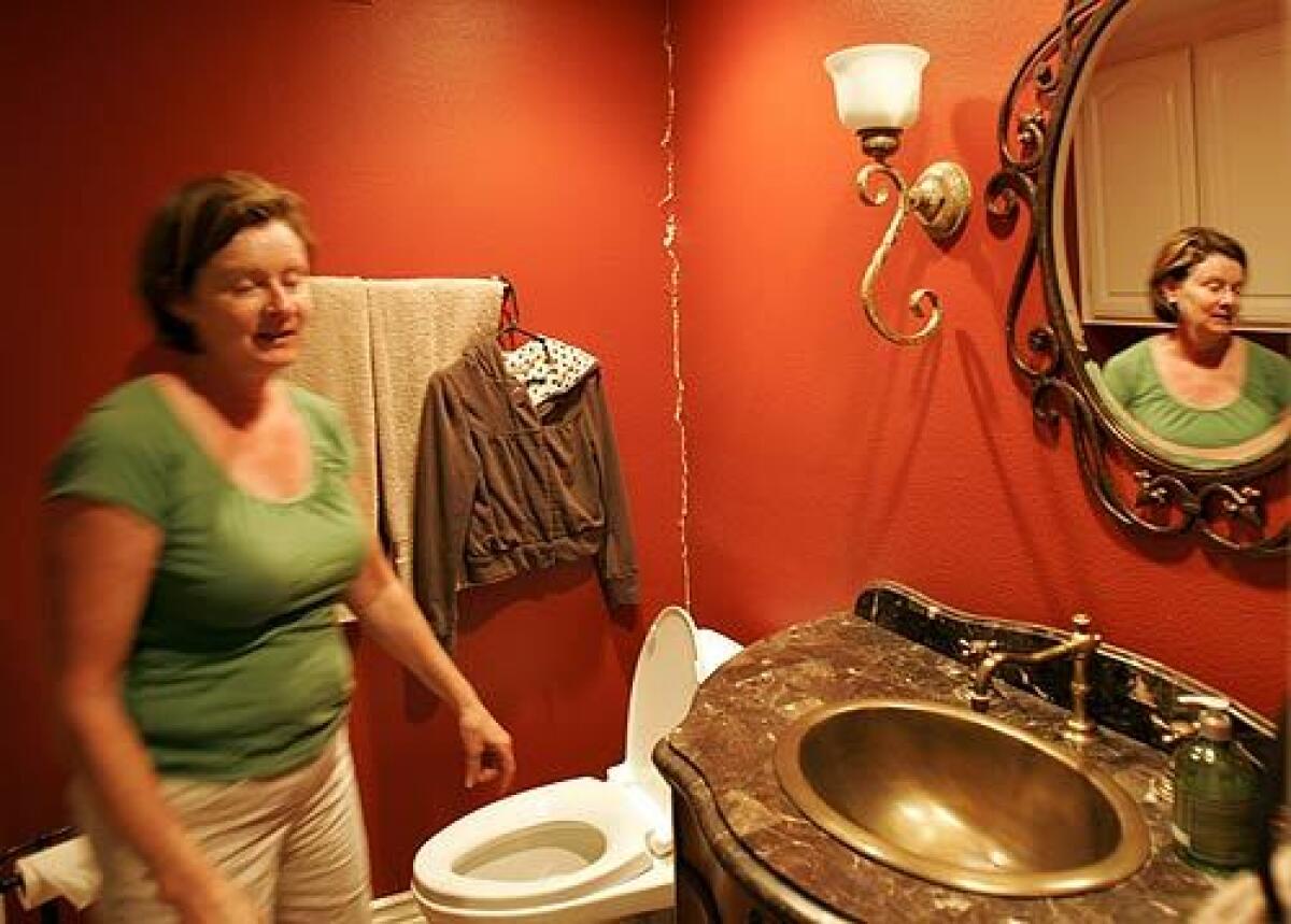 Yorba Linda resident Christi Summers stands in her first-floor bathroom, where a long vertical crack in the drywall was caused by Tuesday's 5.4 earthquake centered in nearby Chino Hills.