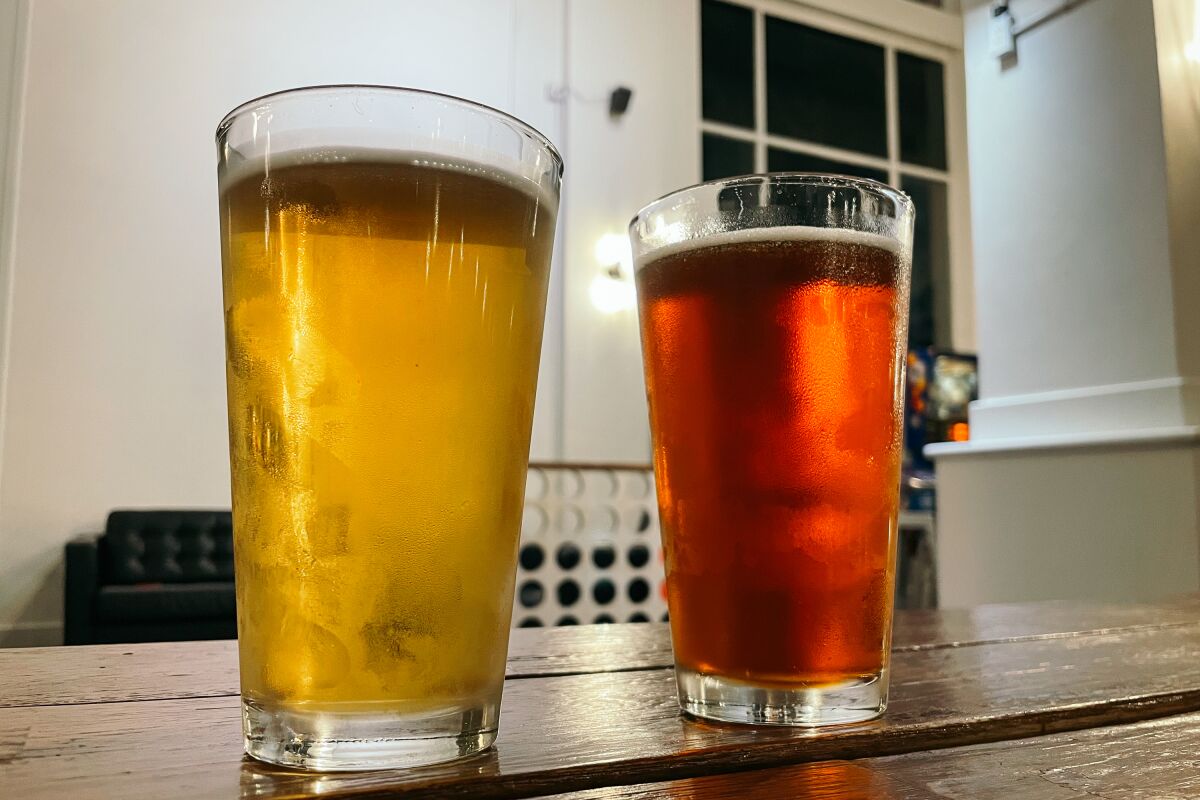 Two pints of beer side by side on a wooden table