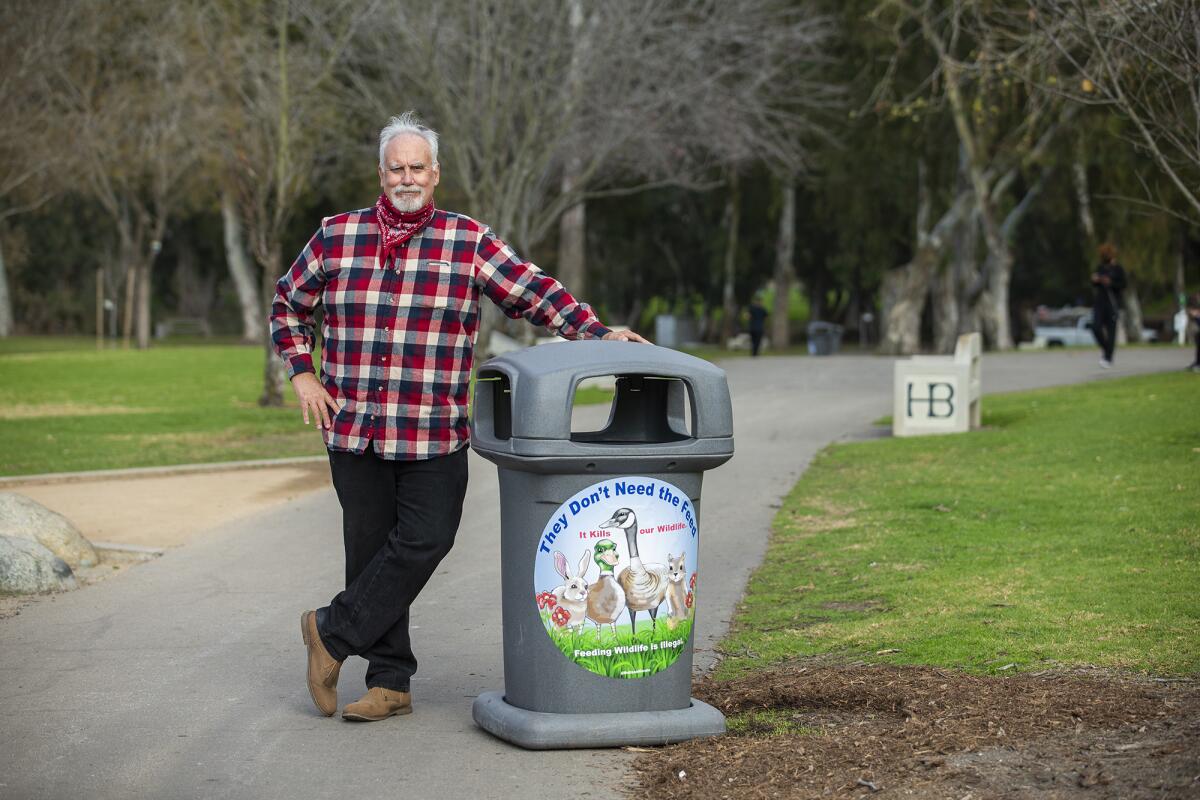 Steve Engel  with a decal urging people not to feed wildlife in Central Park in Huntington Beach.