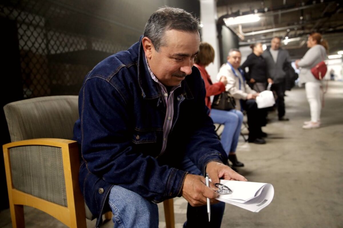 Luis Estrada waits in line in a basement garage to apply for unemployment benefits.
