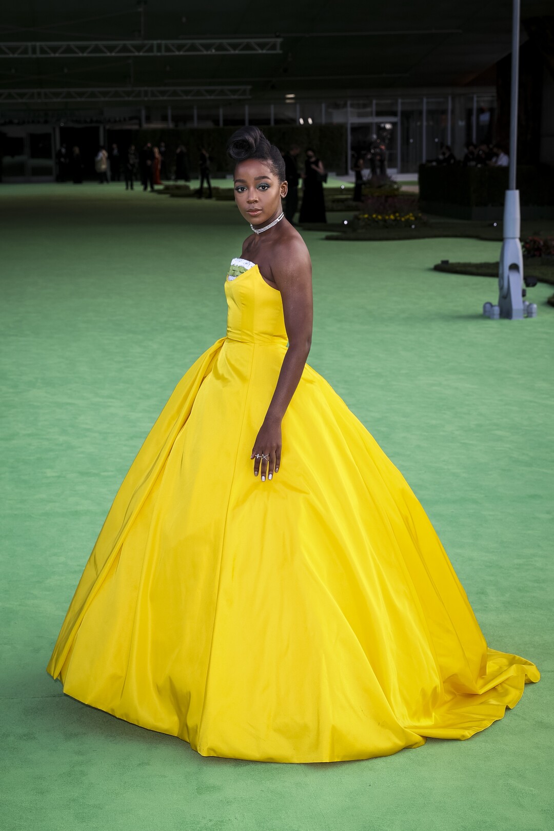 A woman in a yellow dress posing on a green carpet