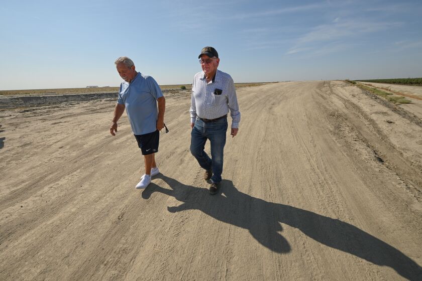 Residents Raul Gomez, 77, (L) and Greg Ojeda, 74, walk together along the Cross Creek Levee in the  farming town of Corcoran