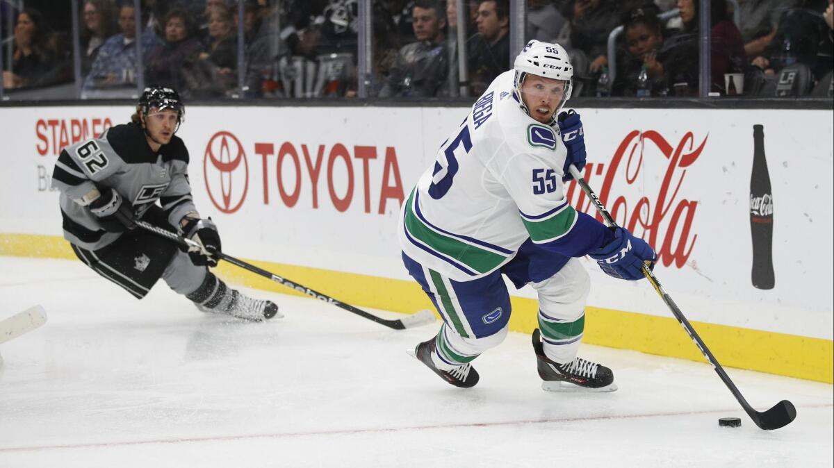 Vancouver Canucks' Alex Biega, right, moves the puck past Kings' Carl Hagelin during the second period on Saturday.