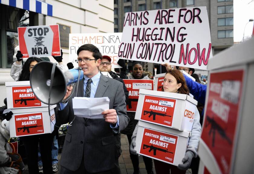 Gun control activists demonstrate at a National Rifle Assn. news conference in Washington. Though a clamor for gun control is rising, some states are moving to ease gun rules and allow certain school staff members to come to work armed.
