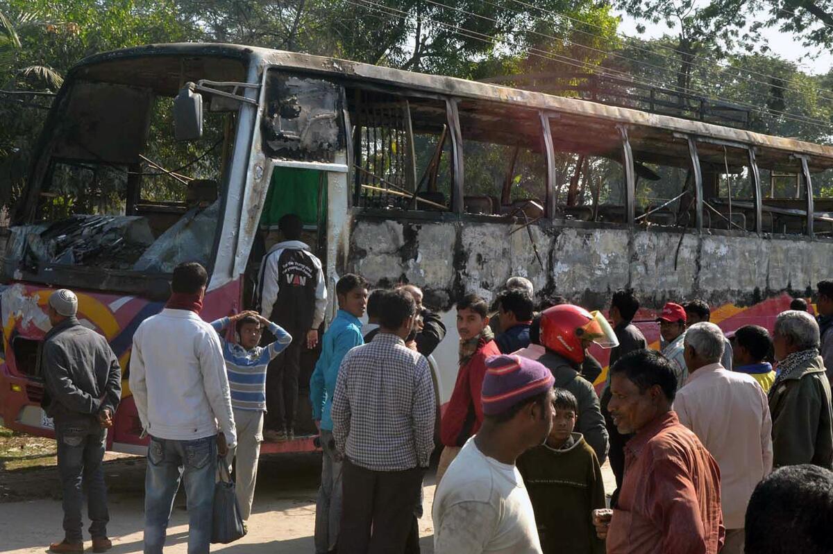 Onlookers surround the wreckage of a bus in Rangpur, Bangladesh, on Wednesday. Five people died when demonstrators attacked the bus with a gasoline bomb.