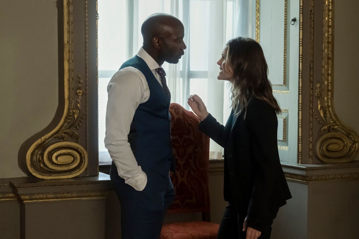 David Gyasi as Austin Dennison and Keri Russell as Kate Wyler hold an intense conversation in front of a window.