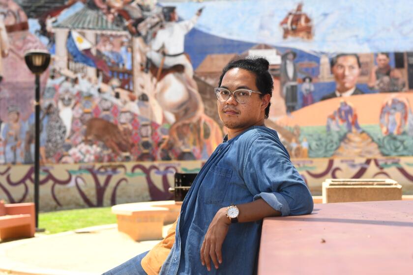 LOS ANGELES, CALIFORNIA JULY 18, 2020-USC professor Adrian De Leon sits in fornt of a mural in Filipinotown area of Los Angeles. DeLeon is currently looking at ways the pandemic affects Americans across racial and socioeconomic lines. (Wally Skalij/Los Angeles Times)