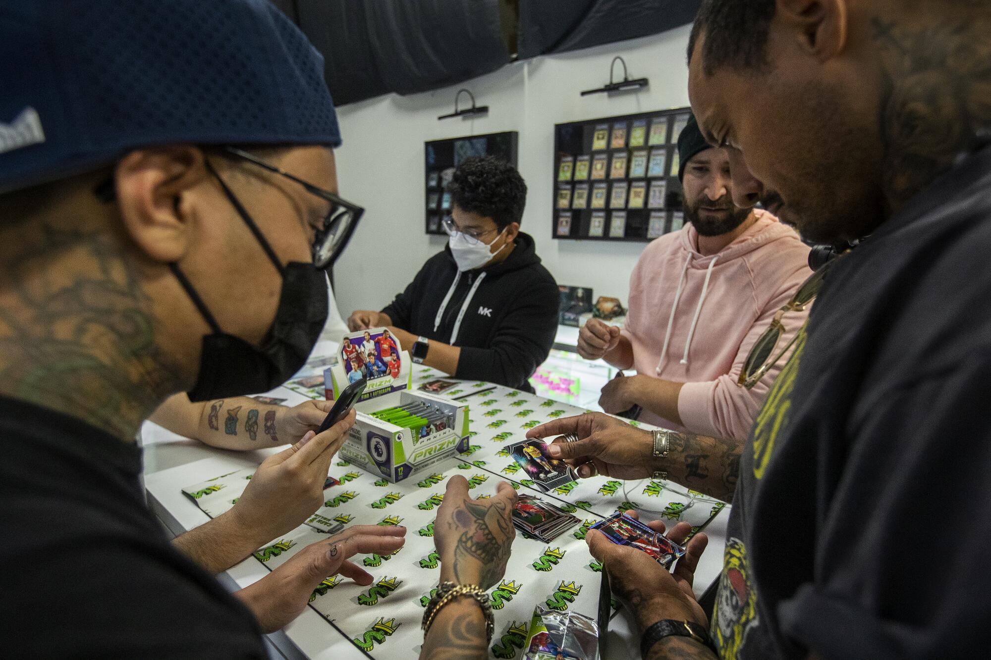 Shop manager and co-founder Chris Cyre, left, watches Jermaine Jones open up a pack of soccer cards.